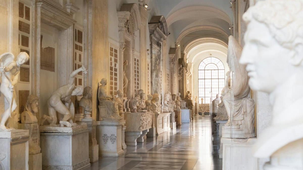 Elegant museum hallway with classical sculptures, showcasing Renaissance architecture and art.