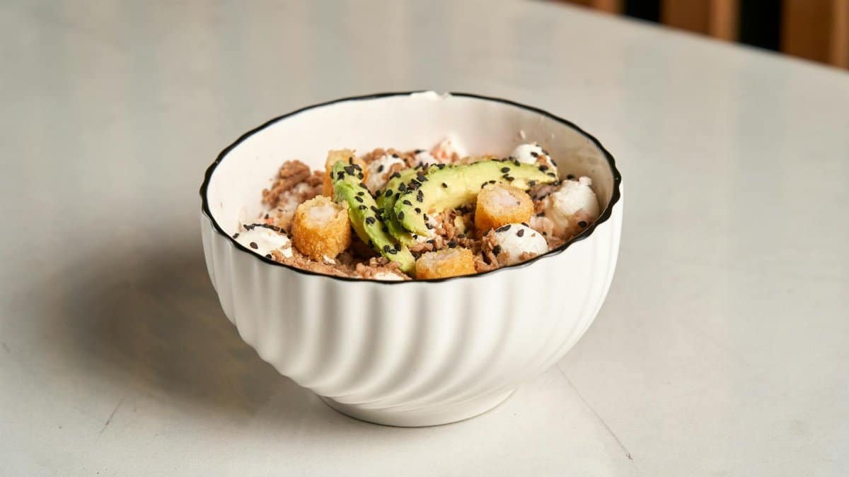 Refreshing salad with avocado, croutons, and sesame in a white bowl.