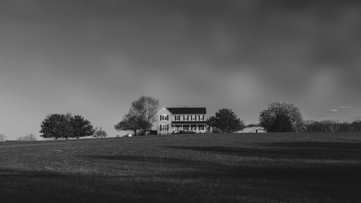 Black and white photo of a solitary house amidst a vast open field in Charlottesville, Virginia.