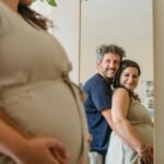 Joyful couple expecting a baby, embracing in front of a mirror indoors.