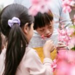 Children explore flowers in a garden, sharing joyful and playful moments outdoors.