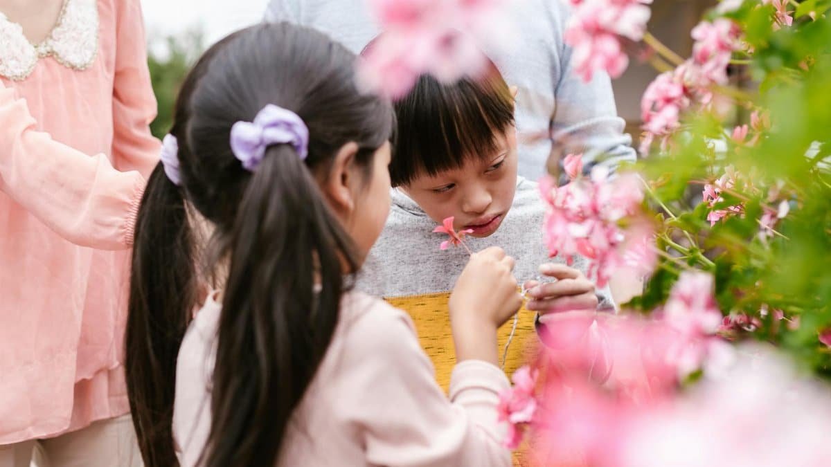 Children explore flowers in a garden, sharing joyful and playful moments outdoors.