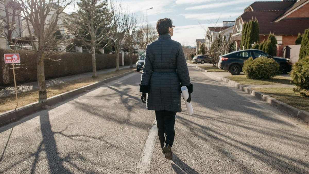 Back view of a woman walking down a suburban street on a sunny winter day.