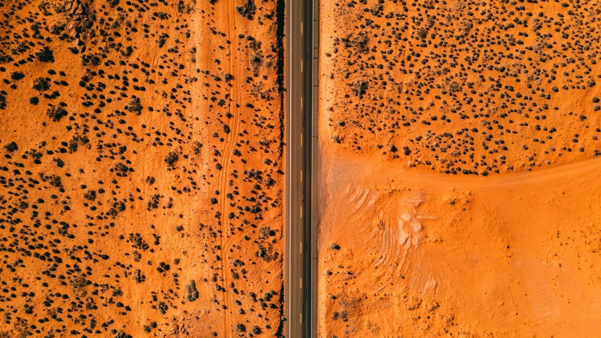 Stunning aerial view of a straight highway cutting through the barren Arizona desert landscape.