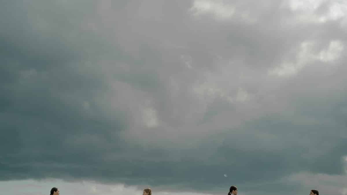 Four people beneath dramatic cloudy skies, evoking modern social themes.