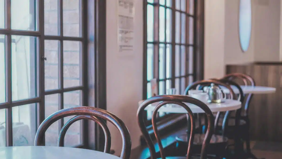 A serene view of a vintage coffee shop with classic wooden chairs and large windows.