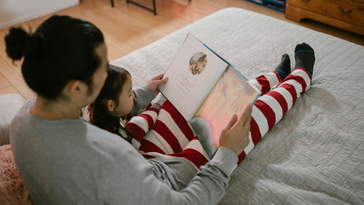 Father and daughter sharing a cozy bedtime story in a warm, home setting.