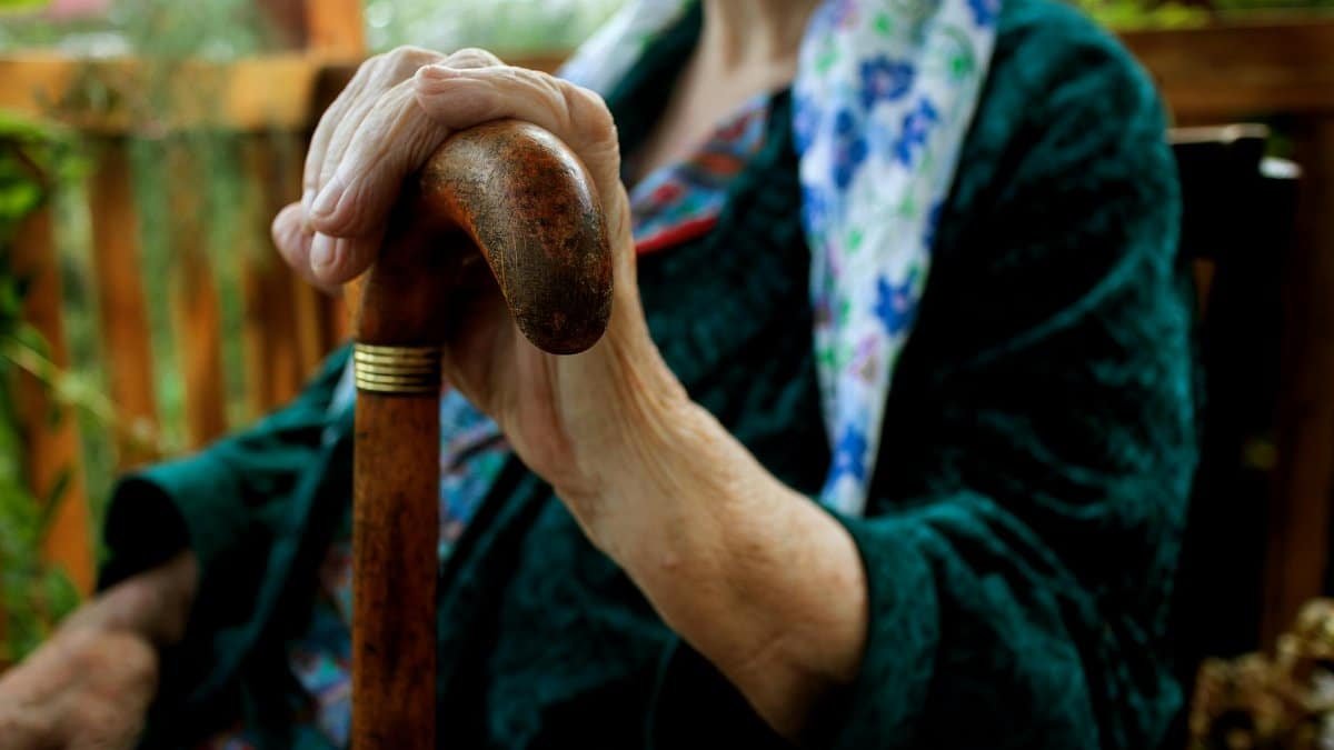 Senior adult holding a wooden cane, symbolizing strength and support.