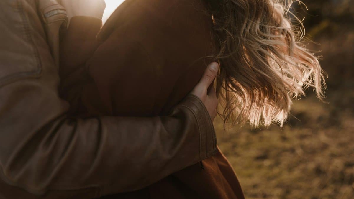 A couple embraces warmly, bathed in the gentle glow of sunset.