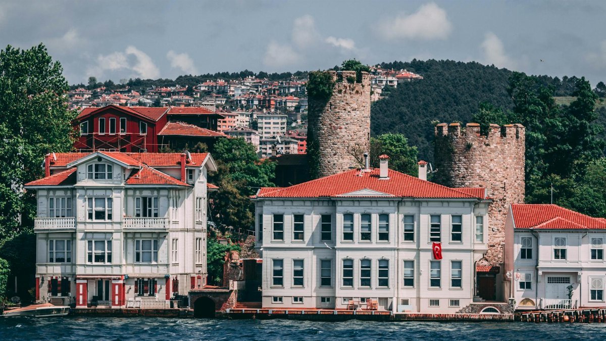 Charming waterfront architecture featuring historical stone towers and vibrant red rooftops by the sea.