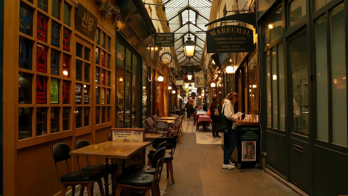 Cozy indoor shopping passage lined with vibrant shops and cafes in Paris, France.