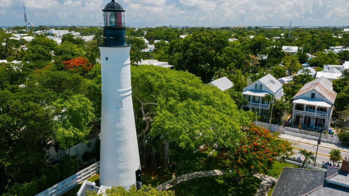 Aerial view of the iconic Key West Lighthouse surrounded by vibrant trees and historic houses.