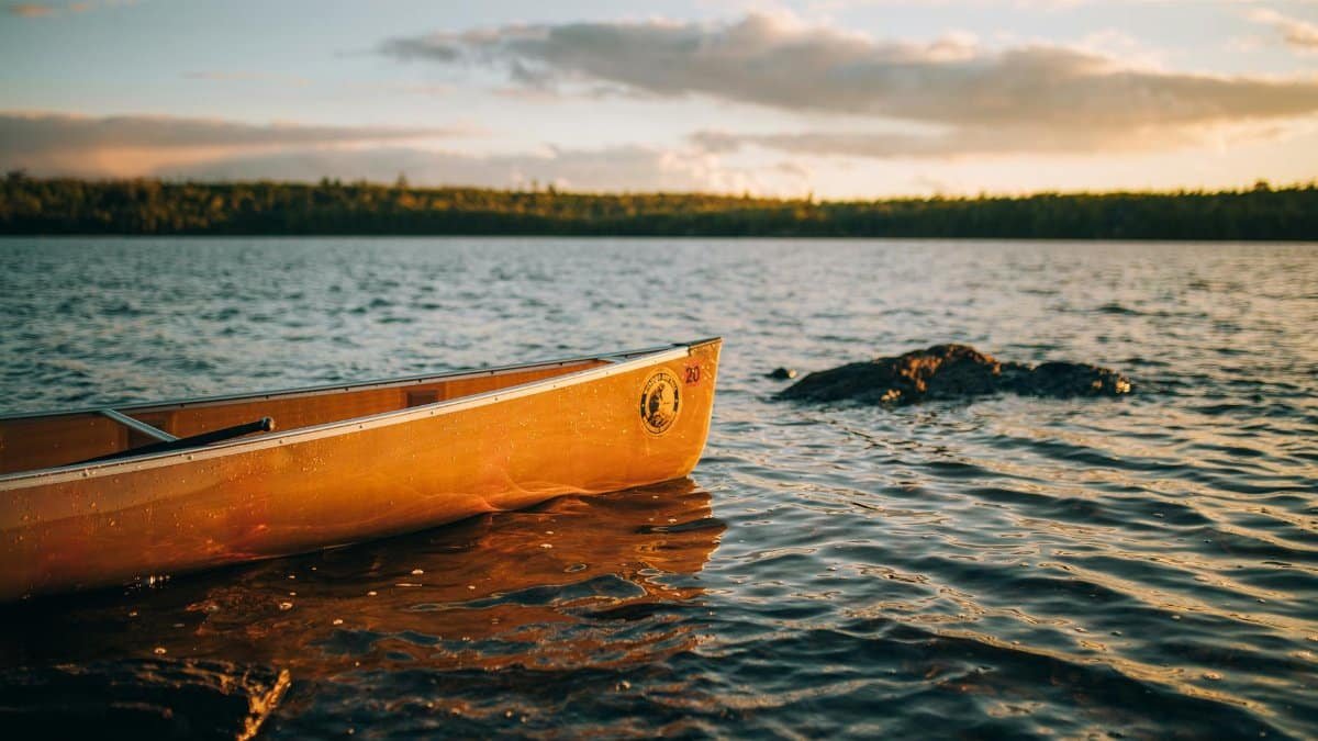 Serene view of a canoe by the lakeside at sunrise, creating a peaceful and adventurous mood in Ely, MN.