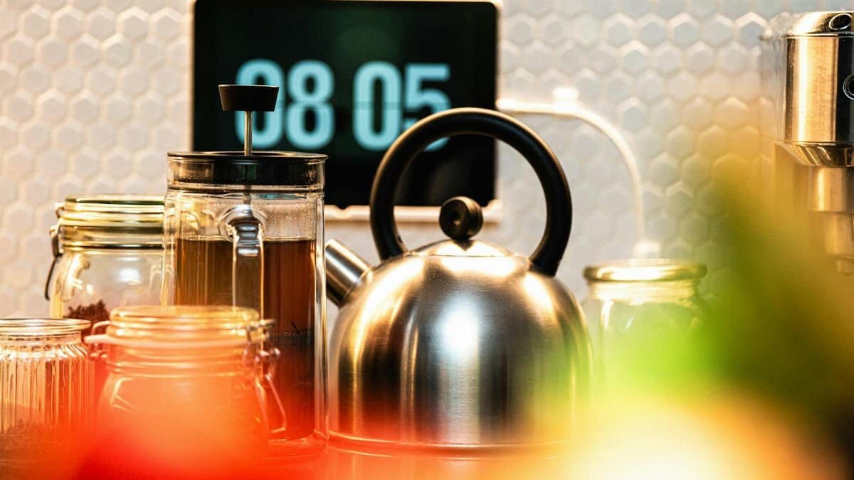 Stylish kitchen scene featuring a French press and kettle with digital time display.