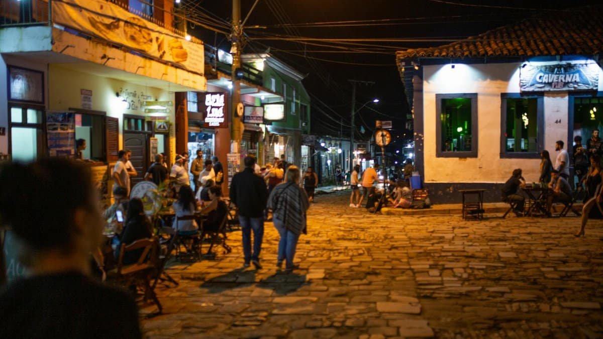 Vibrant nightlife scene with people enjoying cafes and shops on a cobblestone street.