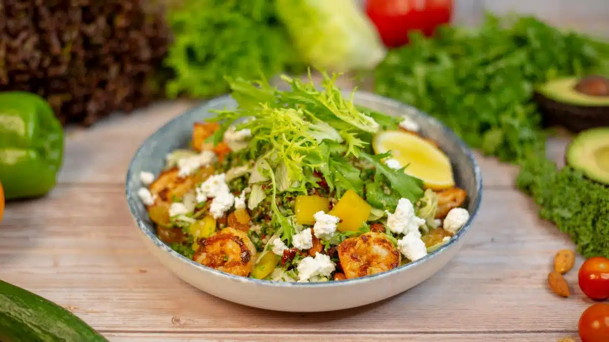 Vibrant quinoa salad topped with fresh vegetables, feta cheese, and lemon slice.