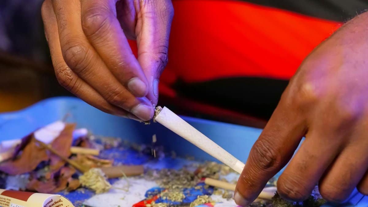 Detailed image of hands rolling a cannabis joint on a blue tray.