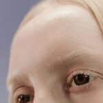 Detailed close-up of a blonde woman's eyes with a neutral background.