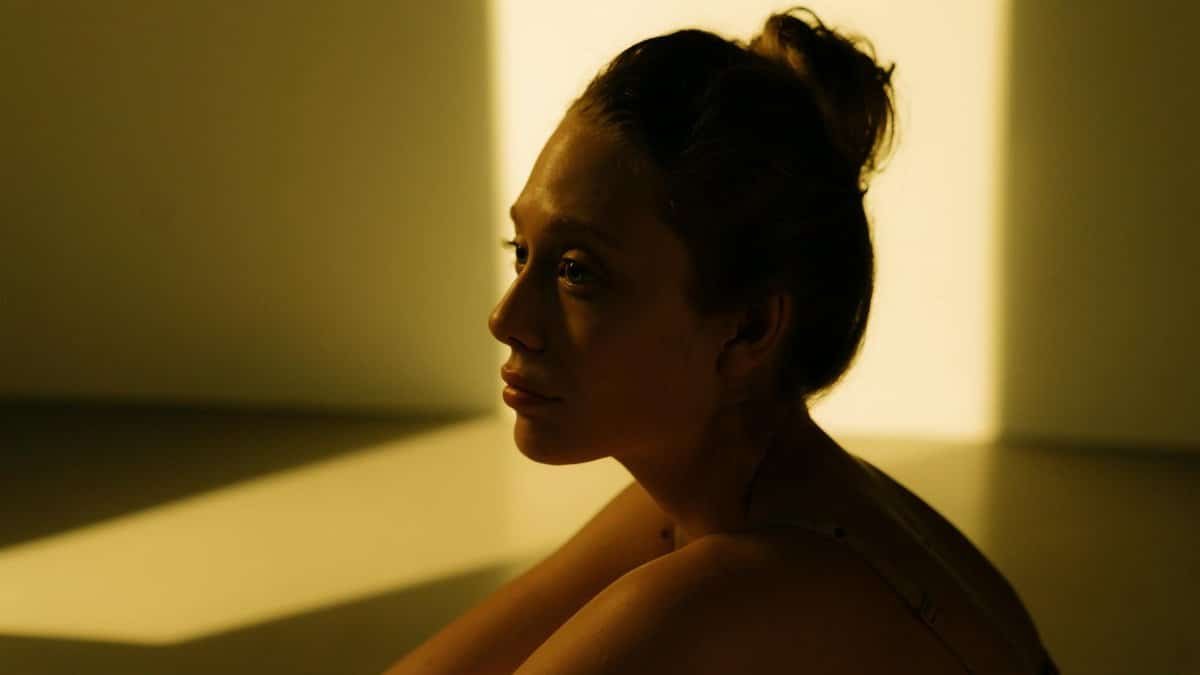 Side view of a woman reflecting in warm sunlight indoors, creating a serene and introspective mood.