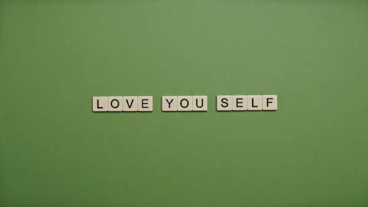 Positive message 'Love You Self' spelled with letter tiles on green background.