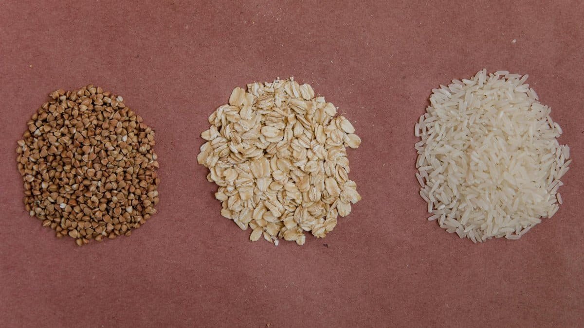 A variety of healthy grains including buckwheat, oats, and rice arranged on a flat surface.