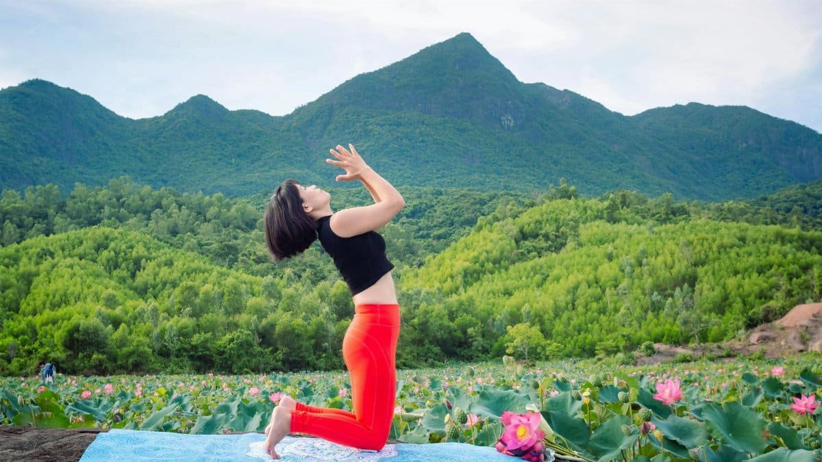 Woman practicing yoga amidst lotus fields in Hội An, Vietnam's serene countryside.