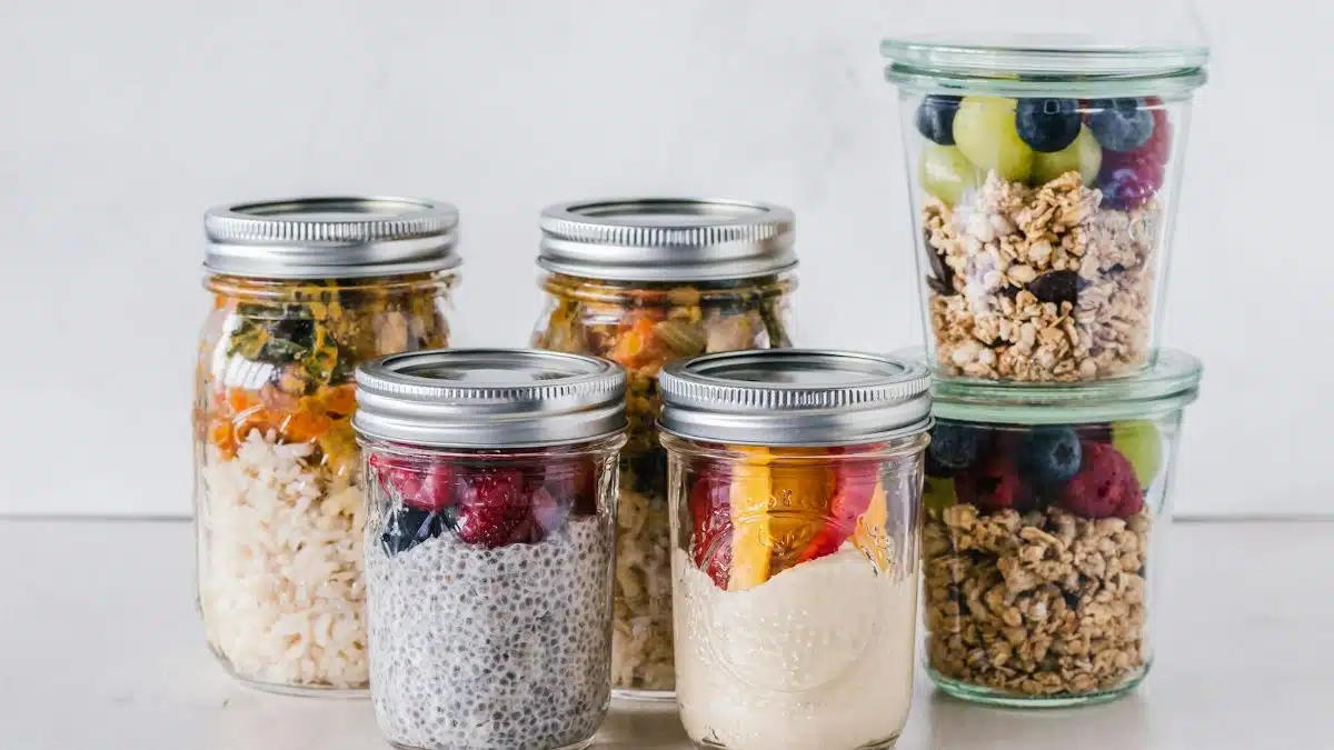 Close-up of healthy food jars containing granola, fruits, and yogurt.