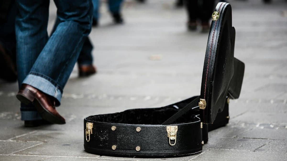 An open guitar case on a busy street, symbolizing live street performances.