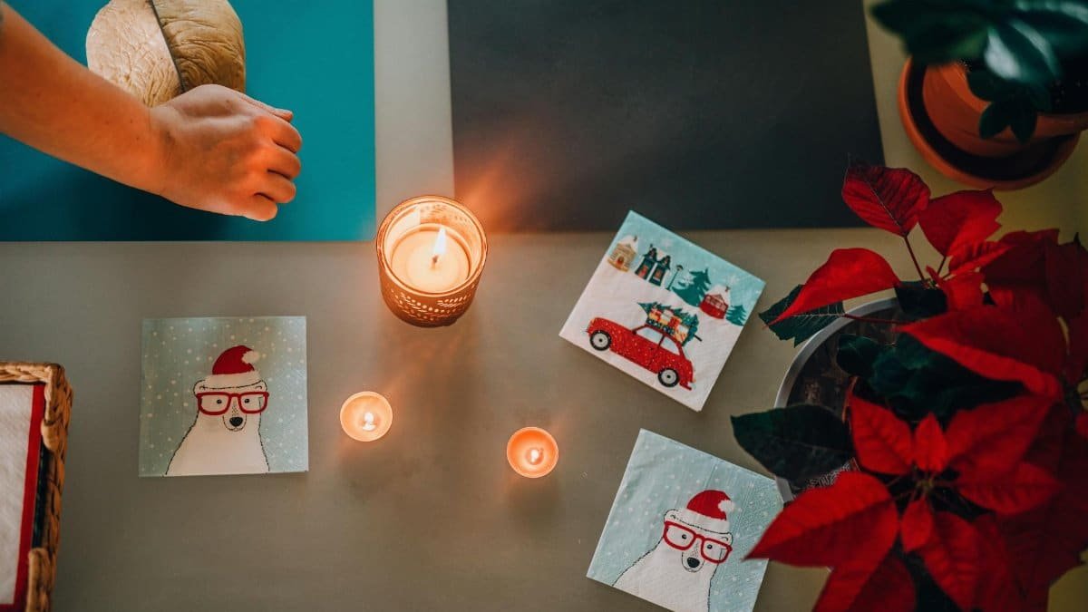 A warm Christmas scene featuring candles, festive cards, and bread preparation.