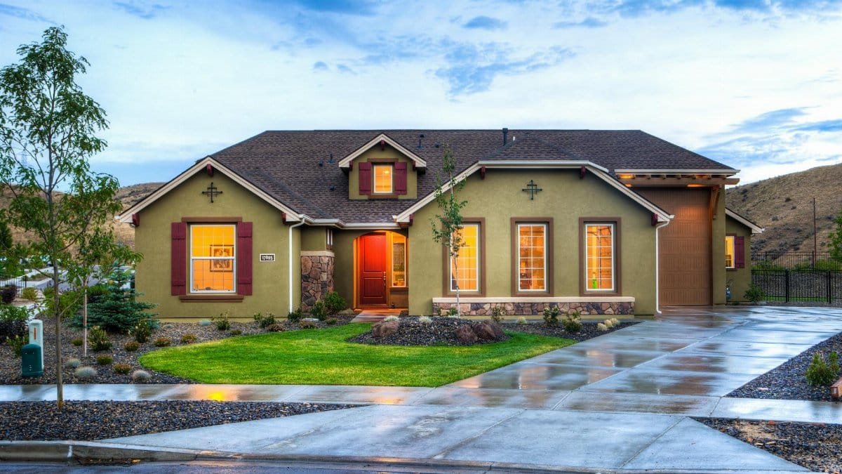 Beautifully illuminated modern home exterior with a lush lawn and wet driveway in Boise, Idaho.