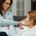 Two women share a moment of comfort and support indoors, expressing emotions.