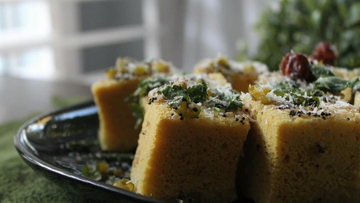 Delicious cornbread topped with herbs and cheese on a ceramic plate, showcasing food styling.