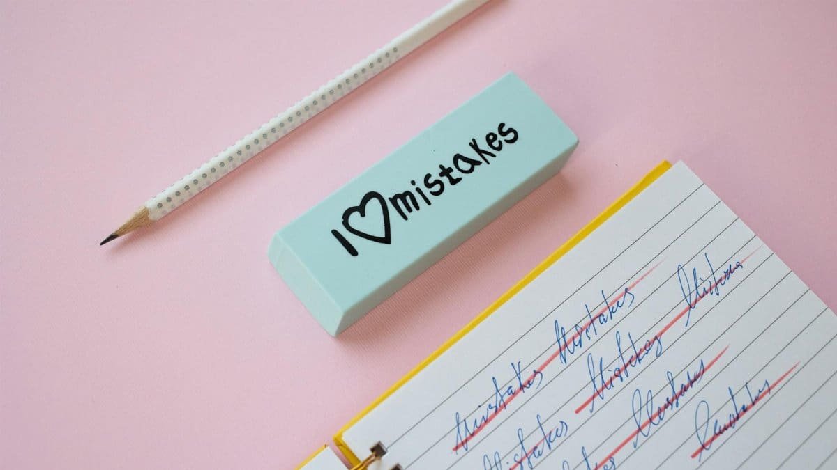 A blue eraser with 'I Love Mistakes' next to a pencil and crossed-out text on a pink background.
