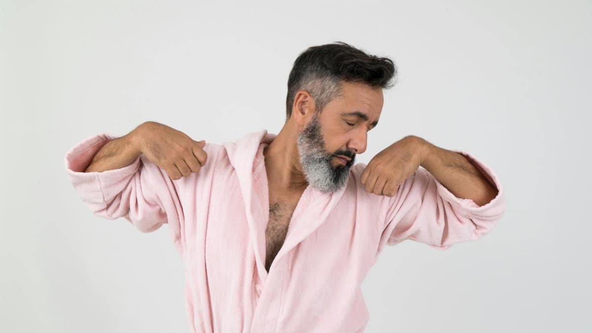 Casual portrait of a relaxed man confidently posing in a cozy pink robe.