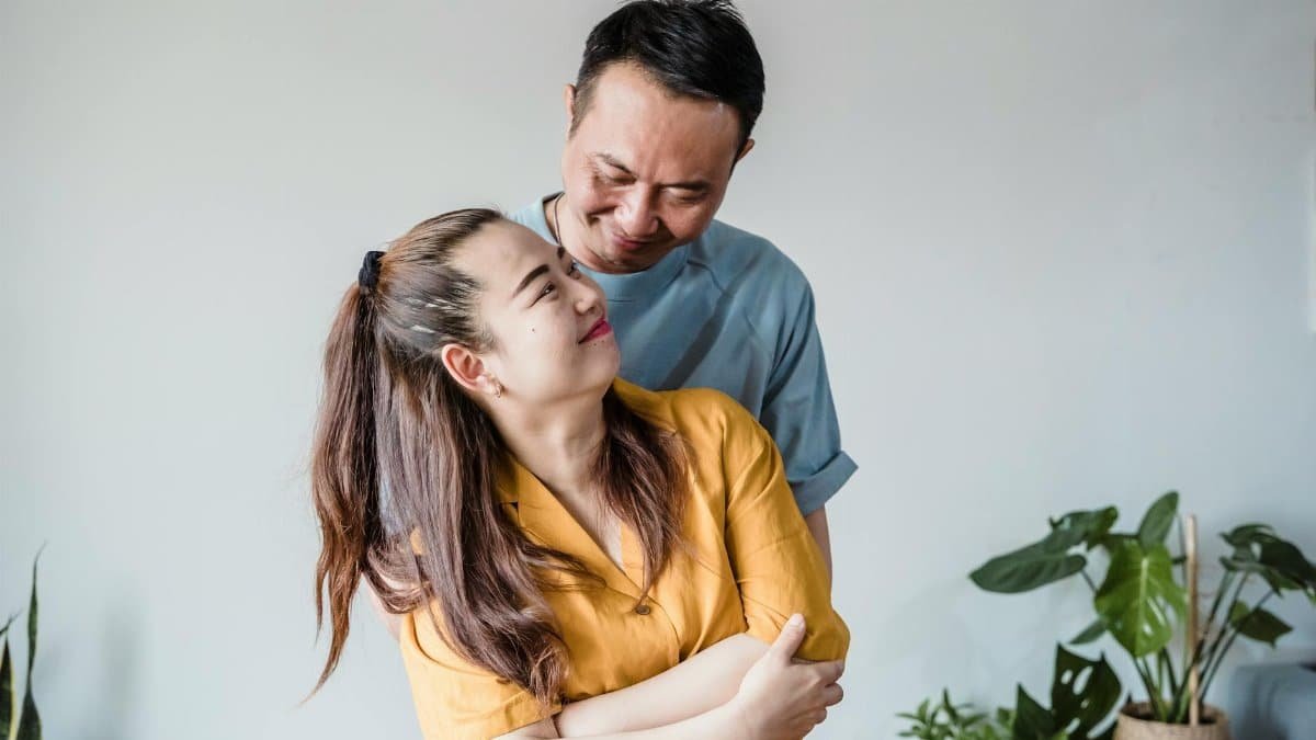 A loving couple sharing a warm embrace indoors surrounded by plants.