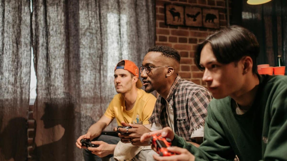 Three men focused on playing video games with controllers indoors.