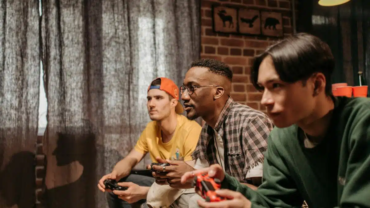 Three men focused on playing video games with controllers indoors.