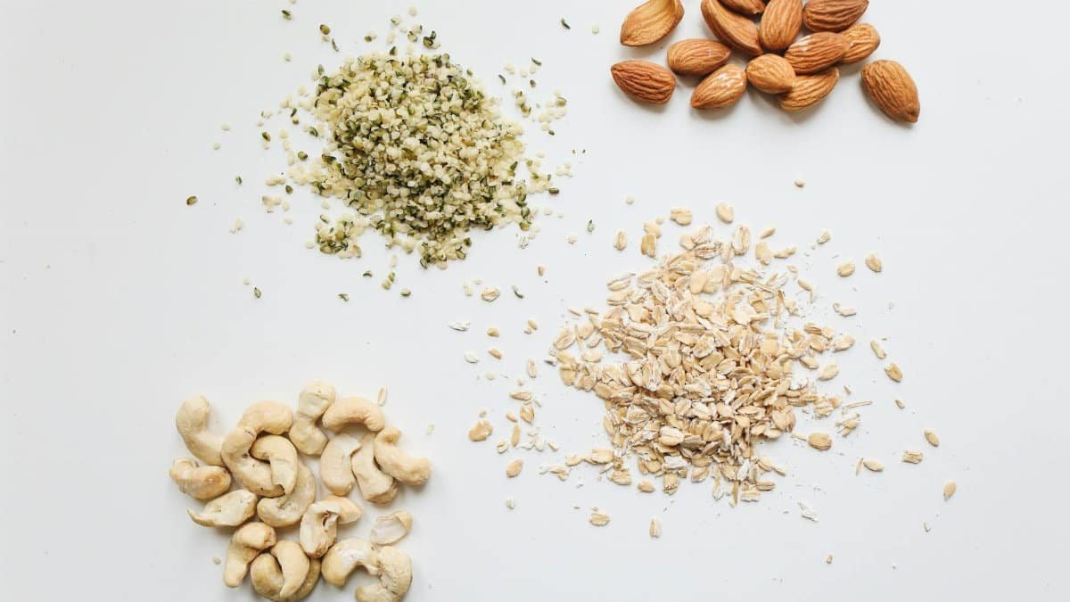 Top view of almonds, cashews, oats, and hemp seeds on white background.