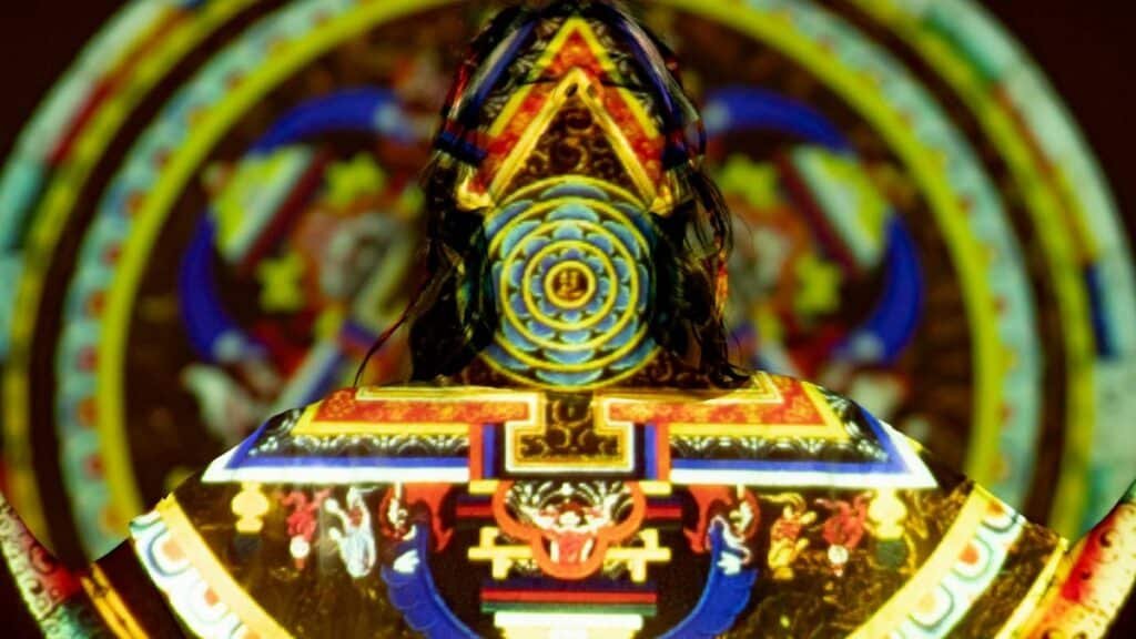 Vibrant projection on woman depicting mystical patterns and spiritual symbols.