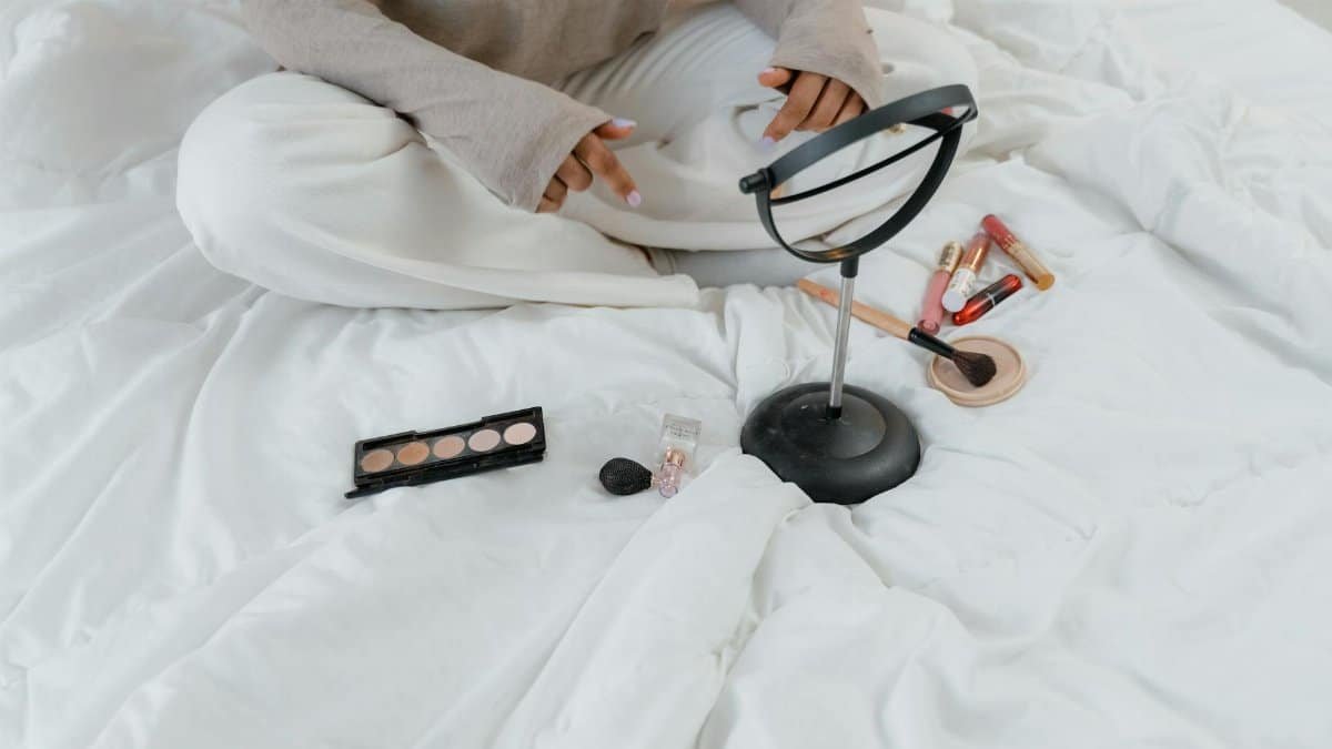 A serene indoor scene with makeup products and a person on a cozy white bed, perfect for lifestyle themes.
