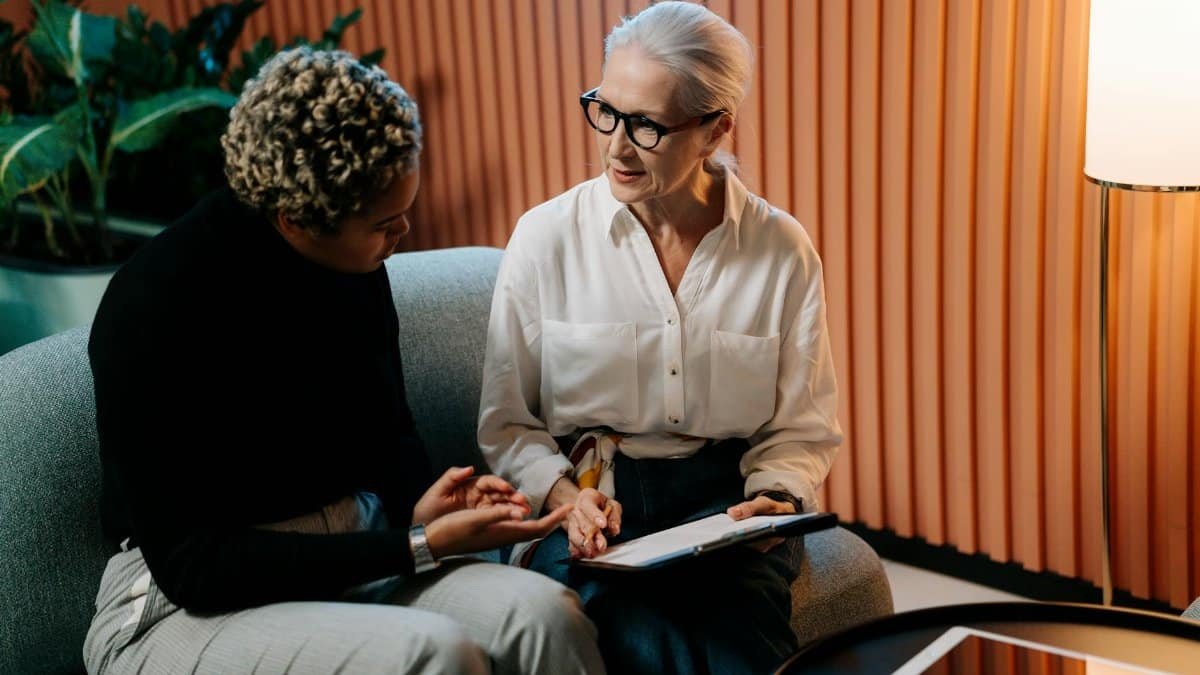 Two professional women engaged in a business discussion indoors with documents.