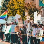 Protesters in Wheeling, WV, hold signs and flags in a diverse, peaceful demonstration on a sunny day.