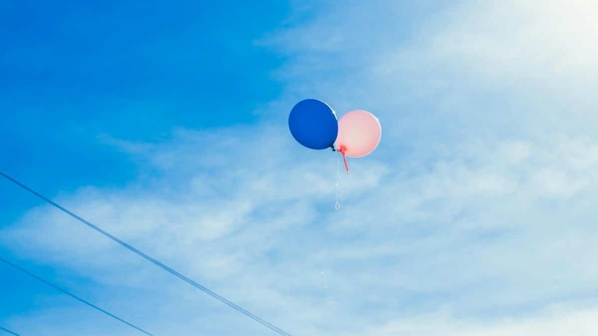 Two balloons floating in a clear blue sky, symbolizing freedom and joy.