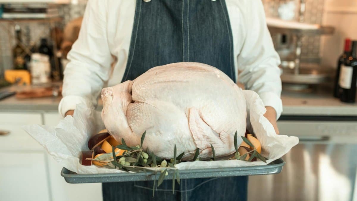 A fresh turkey on a tray, ready for cooking, embodies the Thanksgiving spirit indoors.