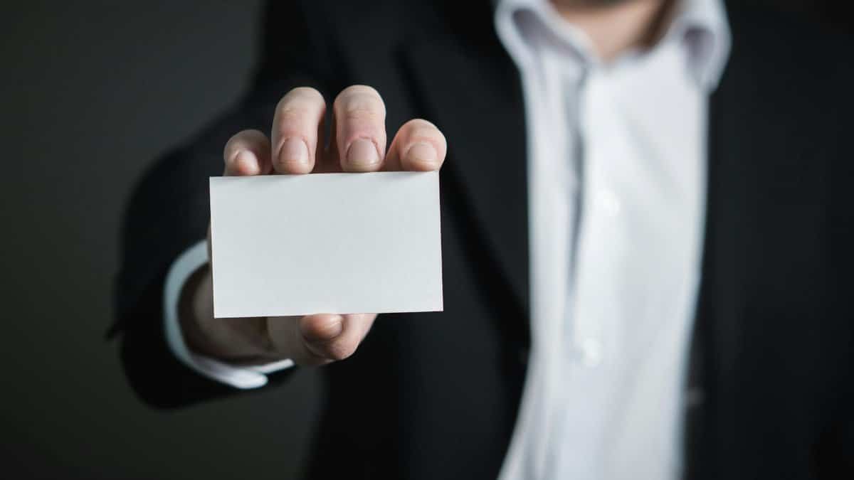 A man in a suit presenting a blank business card for corporate usage.