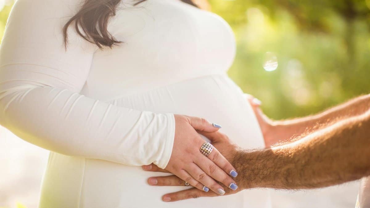 A tender moment showcasing an expectant couple's embrace outdoors.