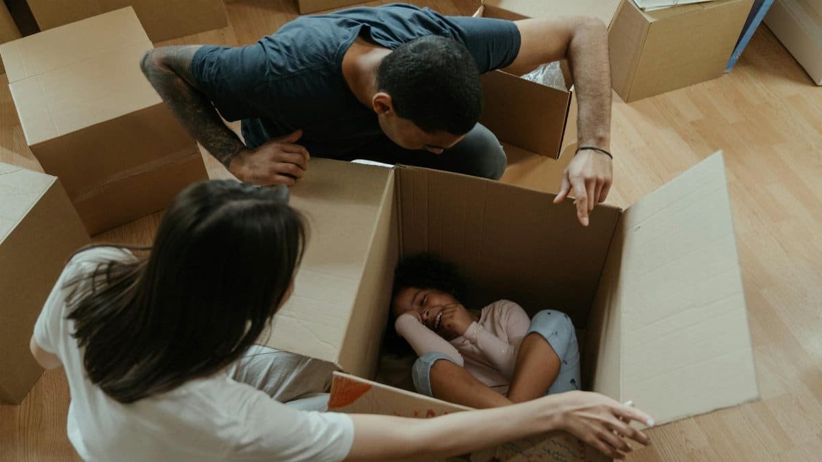 Happy family playing with boxes during moving day, creating joyful memories in their new home.