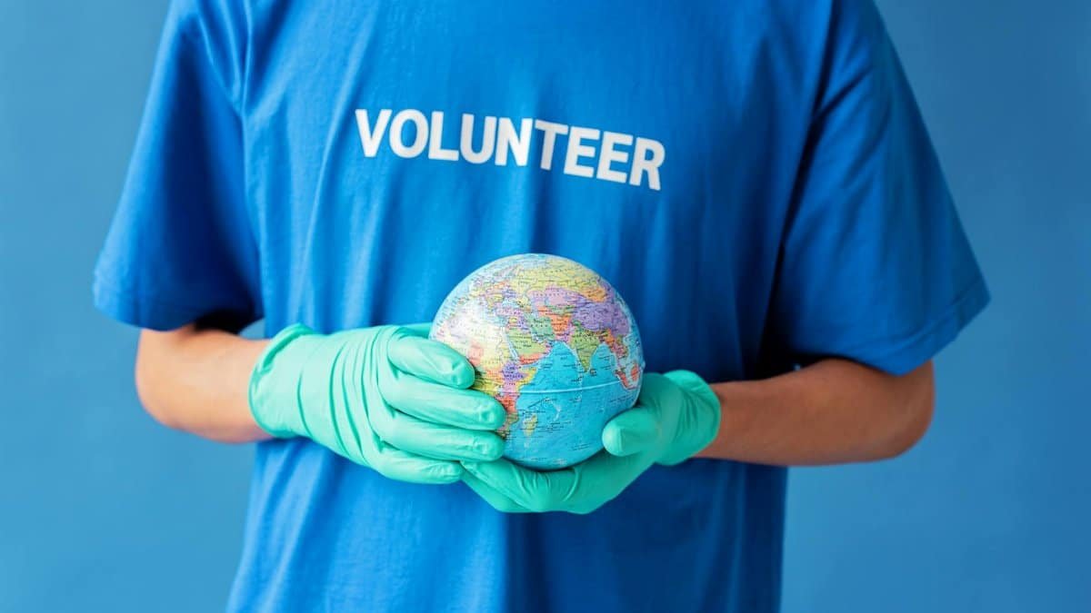 A volunteer in gloves holds a globe, symbolizing global environmental support.