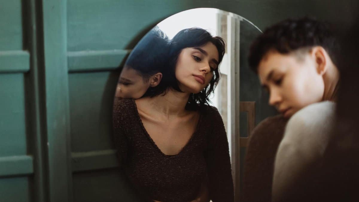 Two people sharing a reflective moment, captured through a mirror in an intimate setting.