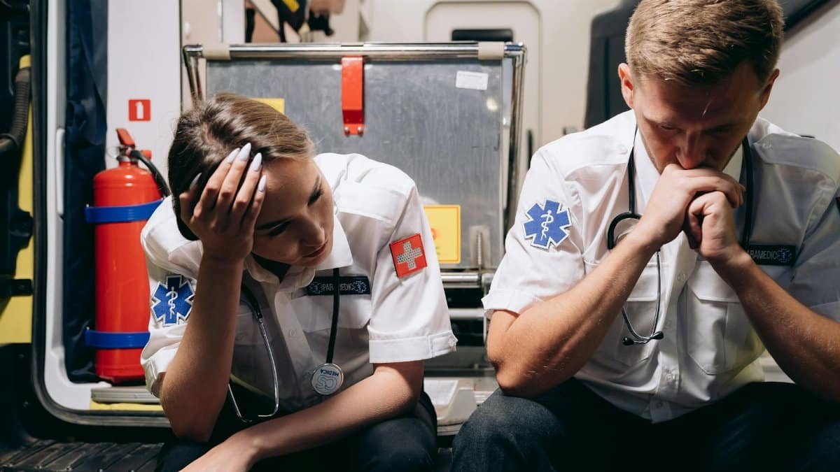 Two tired paramedics sit in the ambulance, reflecting on their challenging day. Emotionally charged moment.